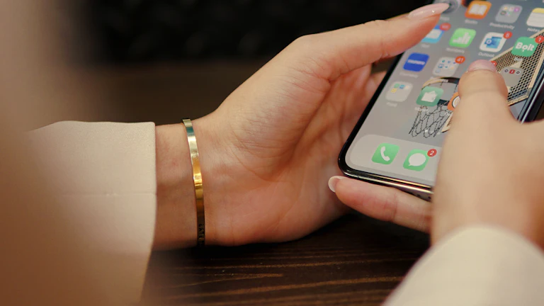 주식 시장 앱이 켜진 스마트폰을 들고 있는 손